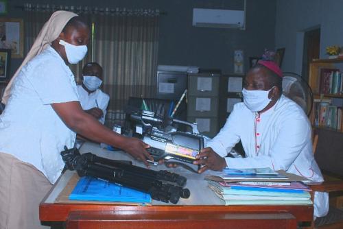 Oyo Diocesan Director of Social Communications, Rev Sr Eunice Ikufisile OSF, presents a newly acquired Sony HD Video Camera to Bishop Badejo in his Office on Tuesday 12th May, 2020 as the Pastoral Secretary, Fr Benjamin Jolasun looks on.